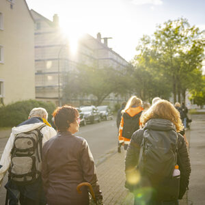 Die Teilnehmenden des Fußverkehrs-Check gehen bei abendlichem Sonnenschein gemeinsam entlang der Route.