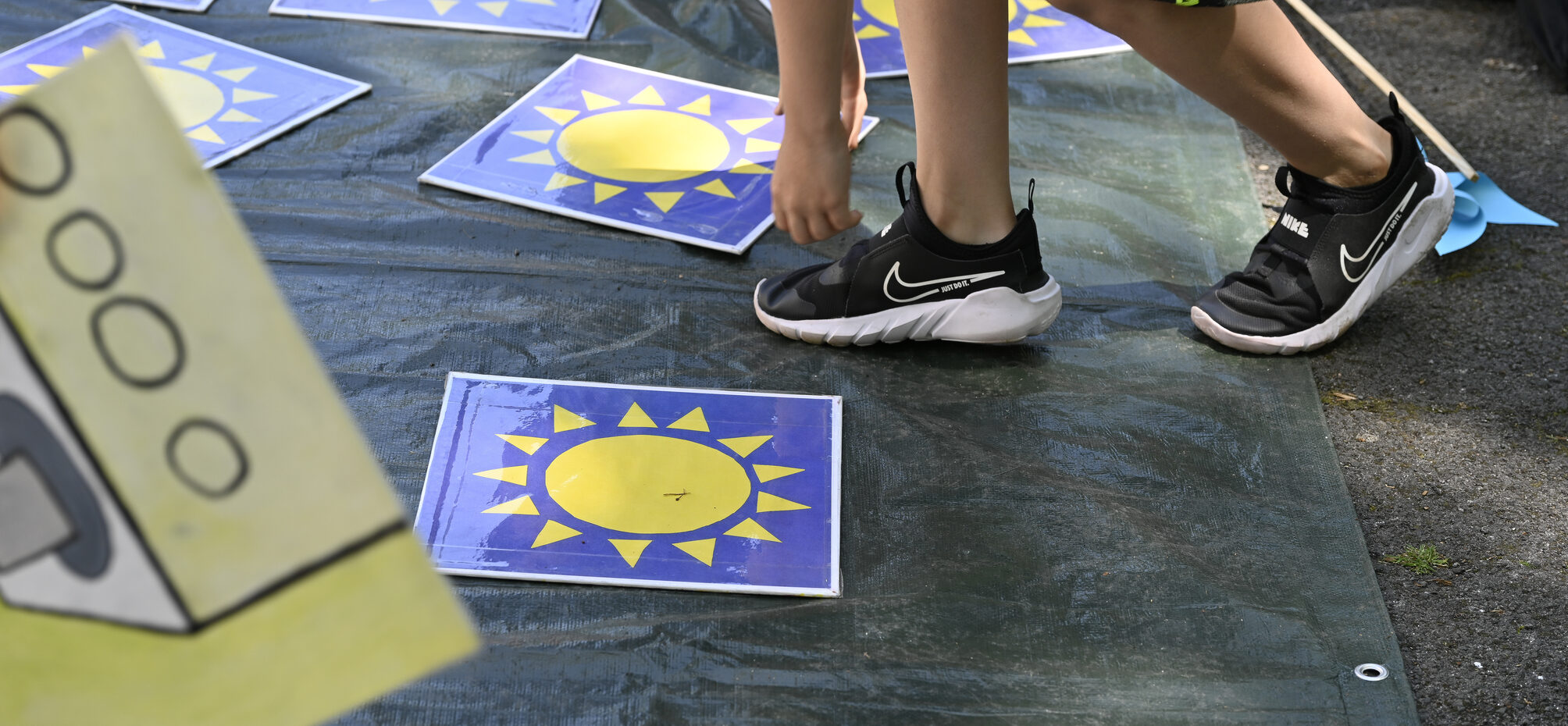 Ein Junge spielt ein Memory-Spiel mit abgebildeten Sonnen auf der Straße.
