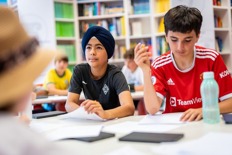 Schüler sitzen nebeneinander an einem Tisch über Arbeitsblättern.