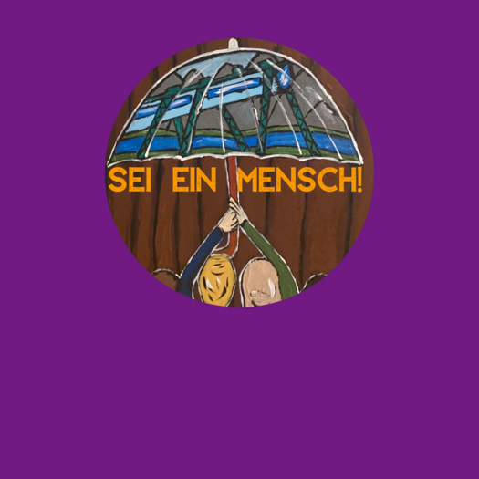 Das Bild zeigt eine Gruppe von Menschen mit unterschiedlichen Hautfarben und Haarstrukturen, die gemeinsam einen großen Regenschirm hochhalten. Auf dem Regenschirm ist die Wuppertaler Schwebebahn abgebildet, während im Hintergrund eine braune Holzstruktur zu sehen ist; darüber steht in gelber Schrift 'SEI EIN MENSCH!'.