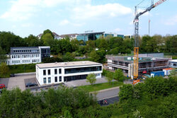 Bestandsgebäude der Ceteq GmbH neben eingerüstetem Neubau