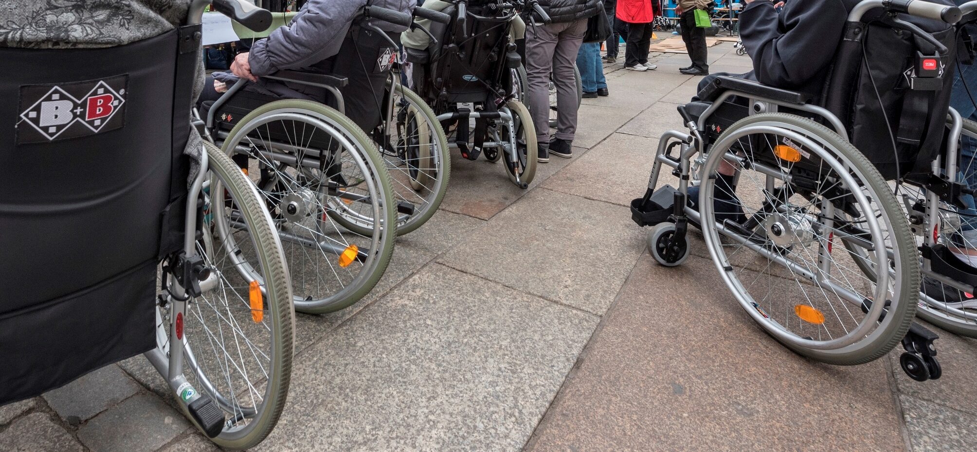 Rollstuhlfahrende Menschen auf einem öffentlichen Platz
