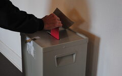 Ein Stimmzettel wird in die Wahlurne geworfen