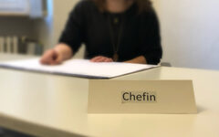 Eine Frau am Schreibtisch mit dem Schild "Chefin"
