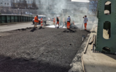 Arbeiter tragen auf der Islandbrück einen neuen Straßenbelag auf