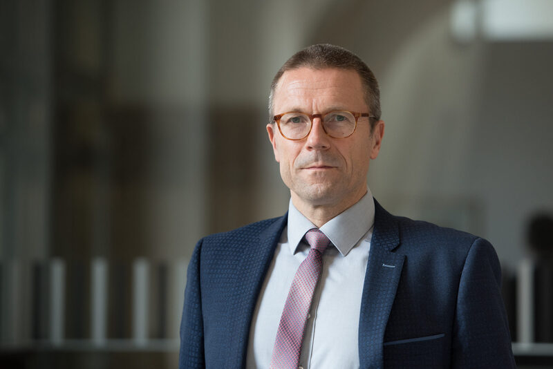 Portrait Oberbürgermeister Uwe Schneidewind vor dunklem Hintergrund