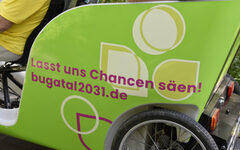 Eine Fahrrad-Rikscha mit der Aufschrift "Lasst uns Chancen säen! Bugatal2031"