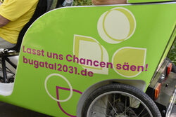 Eine Fahrrad-Rikscha mit der Aufschrift "Lasst uns Chancen säen! Bugatal2031"