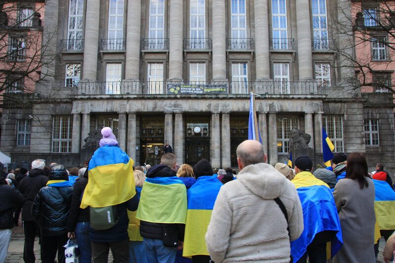 Menschen mit ukrainischen Flaggen vorder Rathausfassade