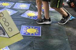 Ein Kind spielt auf der Straße mit einem Memory-Spiel, das Sonnen abbildet.