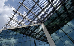 Glasfassade mit Wolken-Spiegelung und Dachkonstruktion