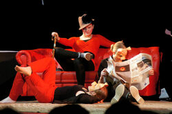 Drei Schülerinnen auf einem roten Sofa auf der Bühne, zwei tragen Schweinsmasken