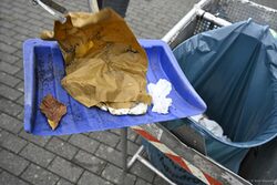 Das Bild zeigt eine Schaufel, auf der Papier und Schaumstoffmüll liegen, die gerade in einen Müllsack wandern