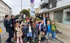 Kinder vor einem Schild das auf den autofreien Weg zur Schule hinweist mit Dezernentin Dr. Katrin Linthorst (2.v.l.)